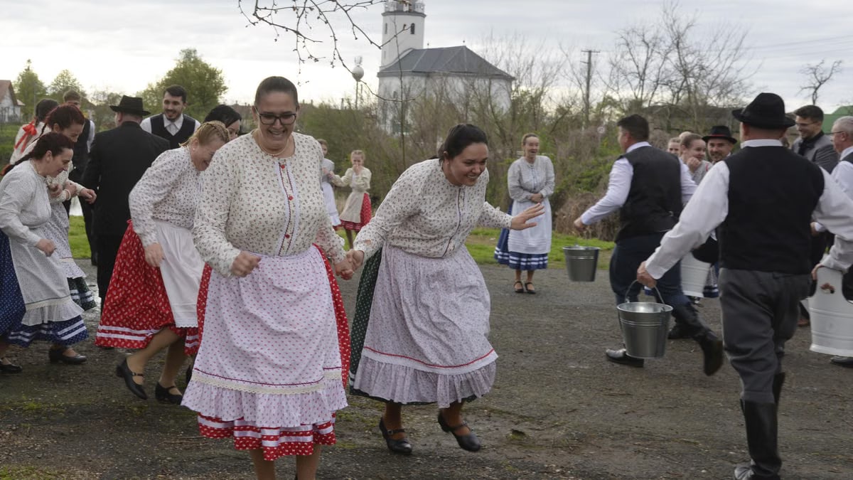 Men pour water on women in traditional Hungarian dress celebrating Easter in Tunyogmatolcs.